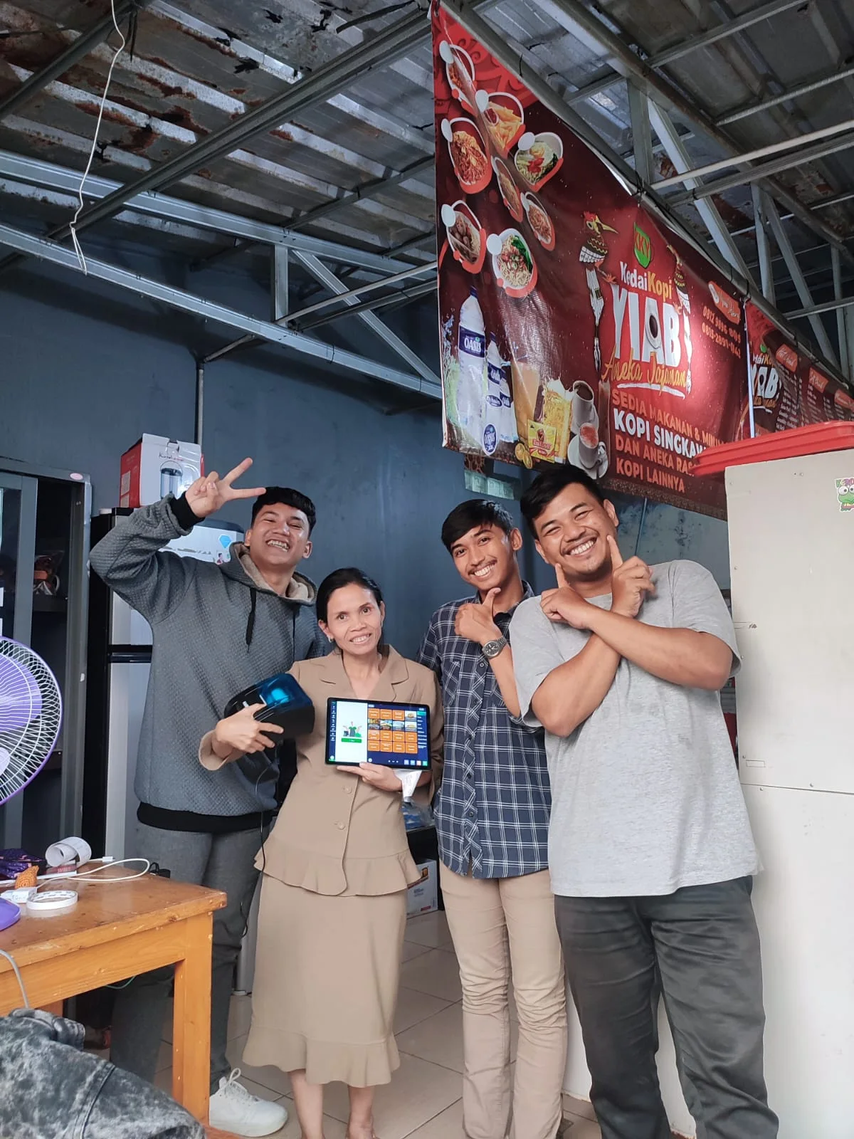 在 Kedai Kopi Yiab 与客户合影，展示收银平板和打印机。